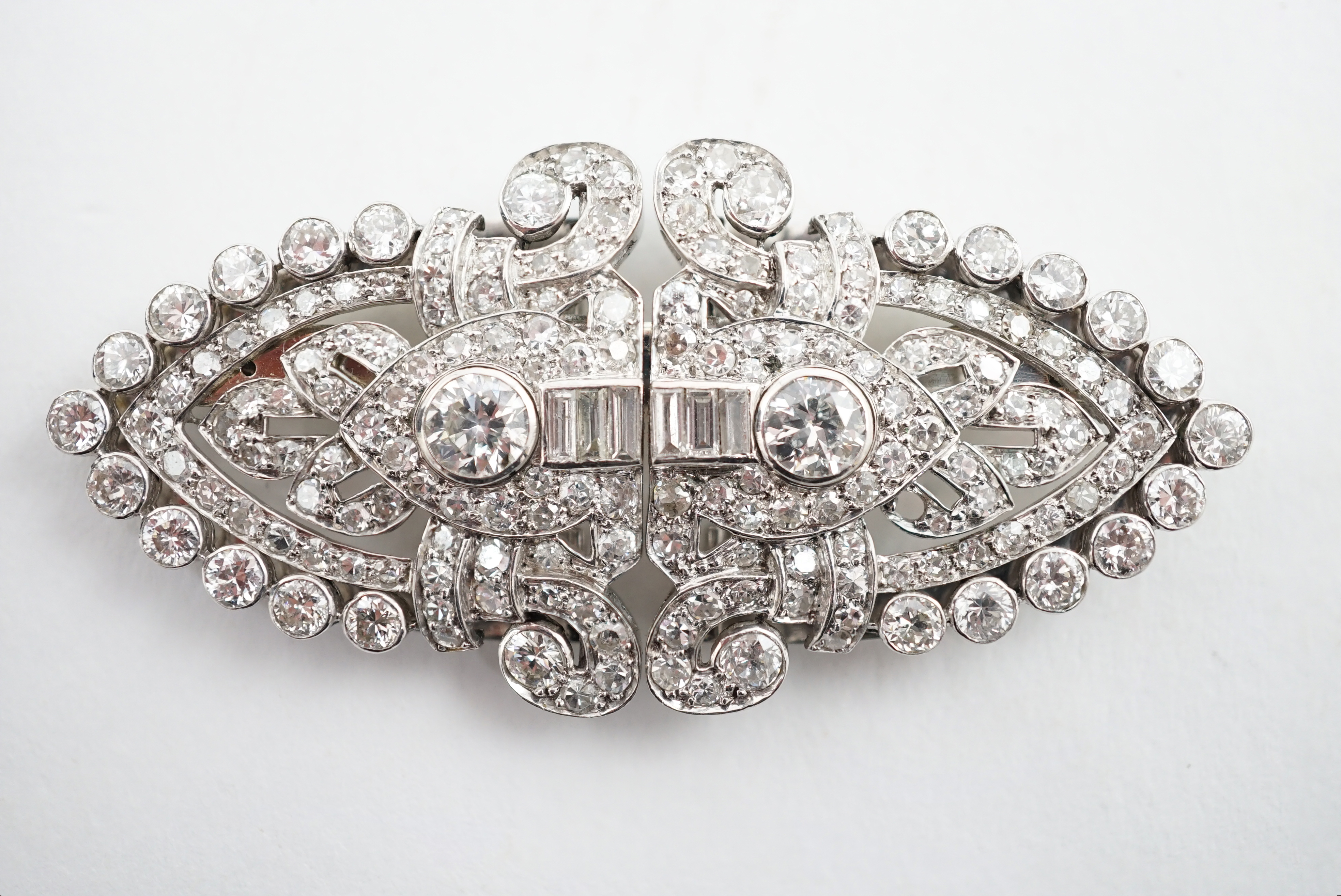 An Art Deco white gold, round and baguette cut diamond set double clip brooch